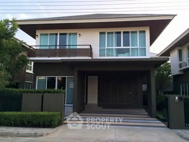 Modern two-story house with large windows and sleek design in a suburban neighborhood.