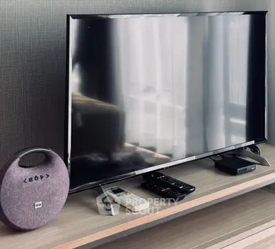 Modern living room setup with sleek TV and stylish accessories on wooden stand.