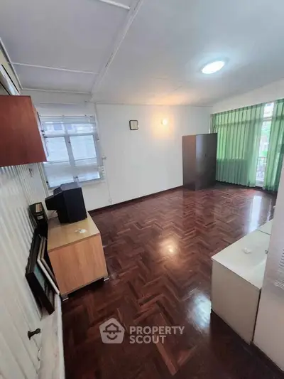 Spacious living room with wooden flooring and large windows for natural light.