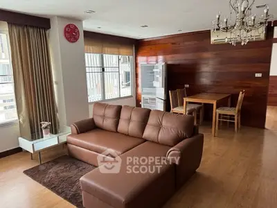 Stylish living room with brown leather sofa and elegant chandelier in modern apartment.