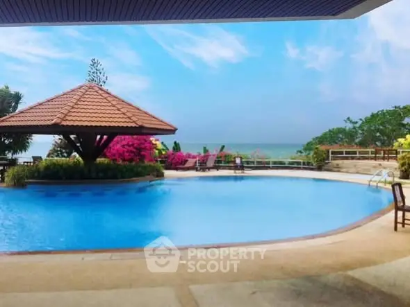 Luxurious poolside view with ocean backdrop and tropical landscaping.