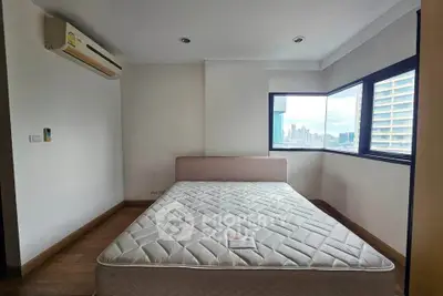 Spacious bedroom with city view and natural light, featuring a comfortable bed and modern air conditioning.