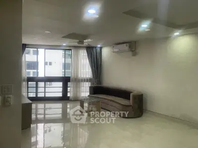 Spacious living room with modern sofa and large windows in a high-rise apartment.