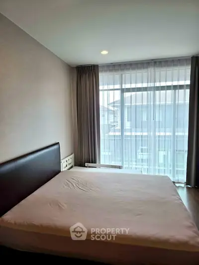 Modern bedroom with large window and natural light in a stylish apartment.