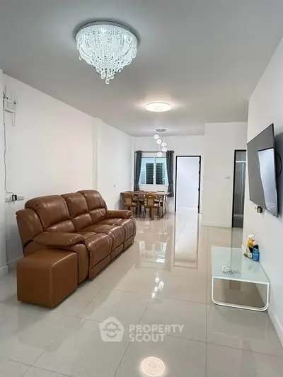 Spacious modern living room with elegant chandelier and leather sofa