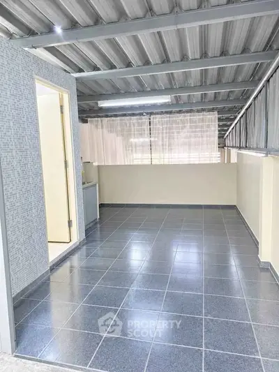 Spacious tiled balcony with modern roofing and ample natural light, perfect for relaxation or entertaining.