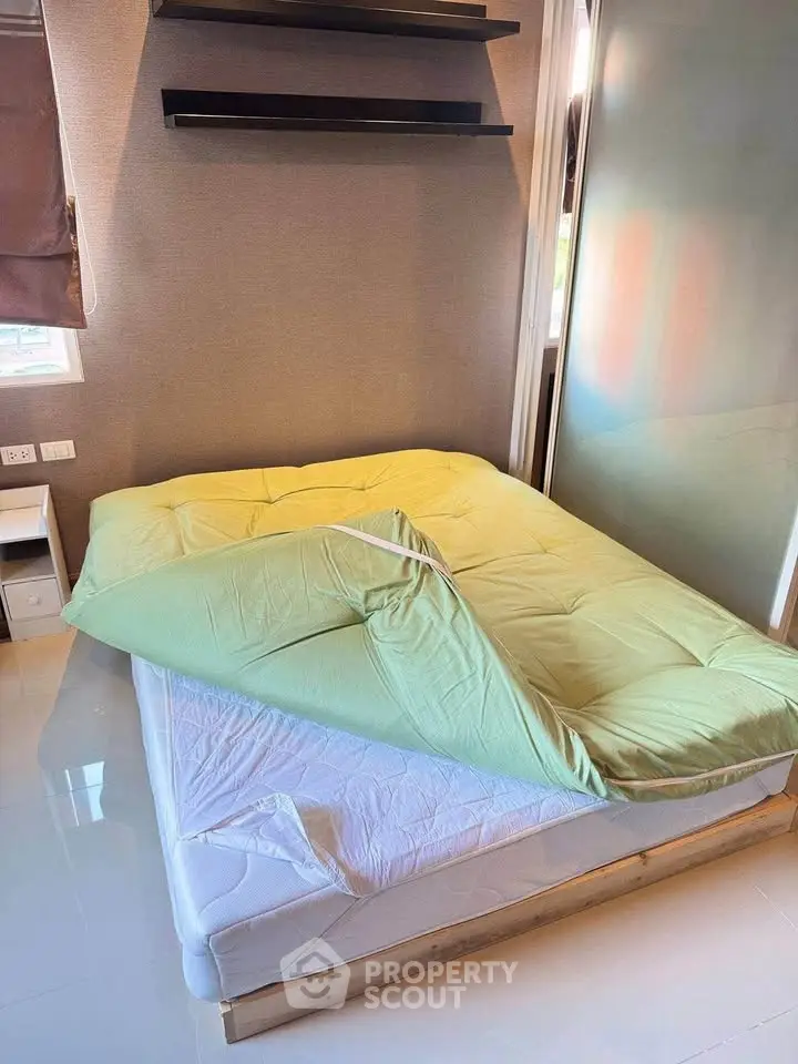 Cozy bedroom with modern decor and natural light, featuring a comfortable bed and sleek shelving.