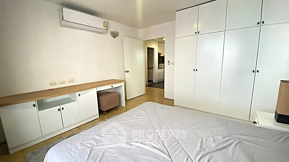 Spacious bedroom with built-in wardrobes and air conditioning in modern apartment.
