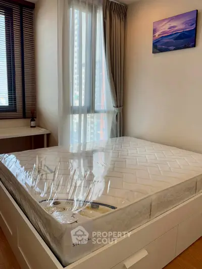 Cozy bedroom with large window and natural light, featuring a new mattress and modern decor.