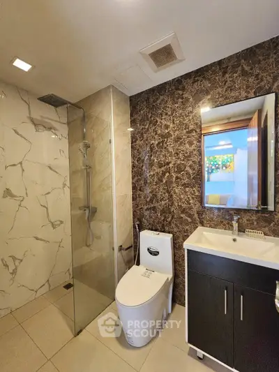 Modern bathroom with elegant marble walls and glass shower enclosure