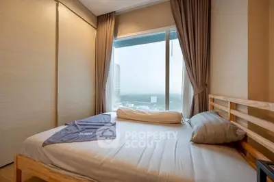 Cozy bedroom with large window offering stunning city view and modern furnishings.