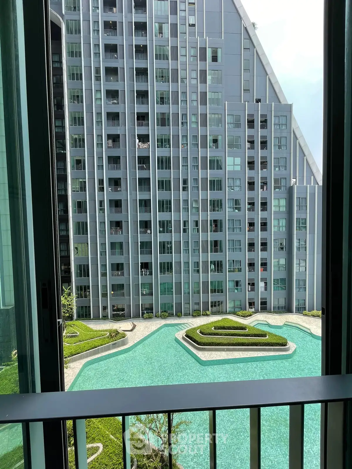 Stunning view from balcony overlooking modern building and pool area.