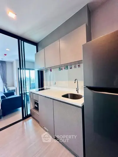 Modern kitchen with sleek cabinets and stainless steel fridge in open layout apartment.
