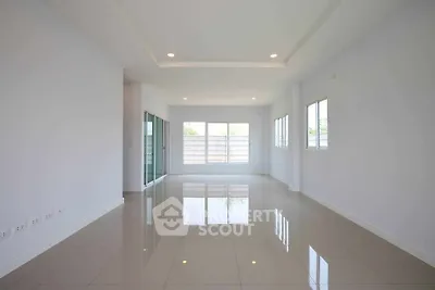 Spacious empty living room with glossy tiled floors and large windows offering natural light.