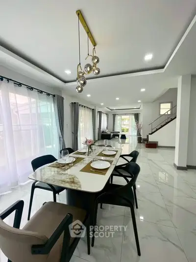 Spacious modern dining area with elegant lighting and marble flooring in a luxurious home.