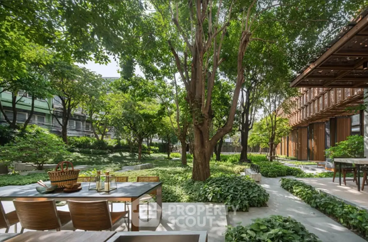 Lush garden with outdoor dining area in a modern residential complex, perfect for relaxation and entertaining.