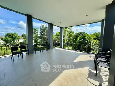Spacious covered balcony with scenic garden view and ample seating.