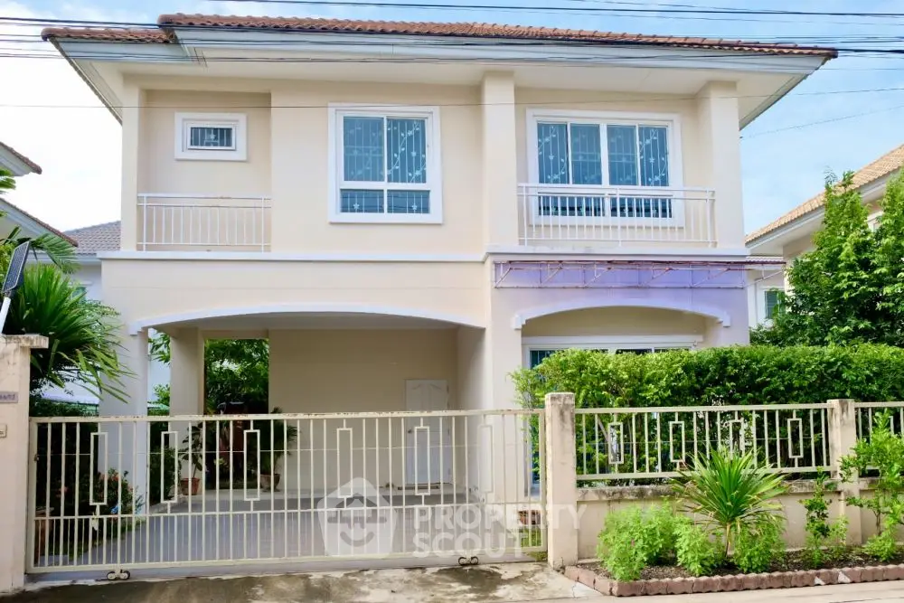 Charming two-story house with gated entrance and lush greenery in a serene neighborhood.