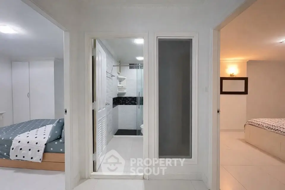 Modern apartment interior with two bedrooms and a central bathroom, showcasing sleek design and ample lighting.