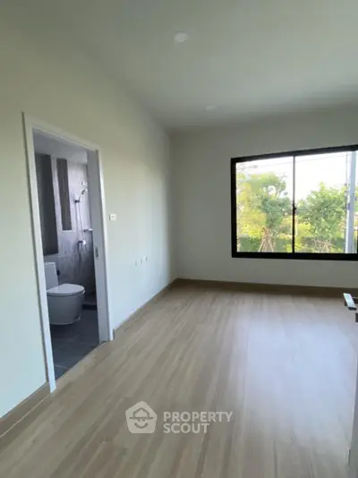 Spacious unfurnished room with large window and attached bathroom, perfect for customization.