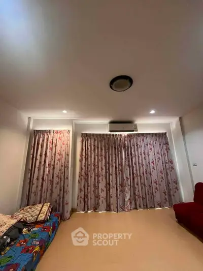 Cozy living room with floral curtains and air conditioning, perfect for relaxation.