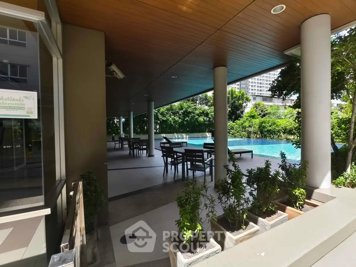 Luxurious outdoor pool area with shaded seating and lush greenery in modern residential complex.