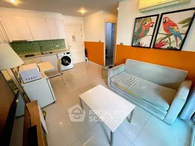 Modern living room with vibrant decor, featuring a compact kitchen and washing machine, ideal for urban living.