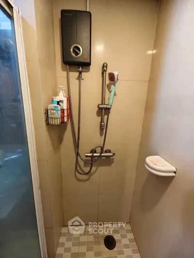 Compact bathroom shower area with modern fixtures and tiled walls.