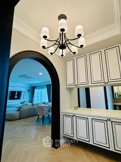 Elegant living room with chandelier and stylish cabinetry, featuring a cozy seating area and modern decor.