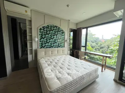 Spacious bedroom with large windows and scenic view, featuring modern decor and natural light.