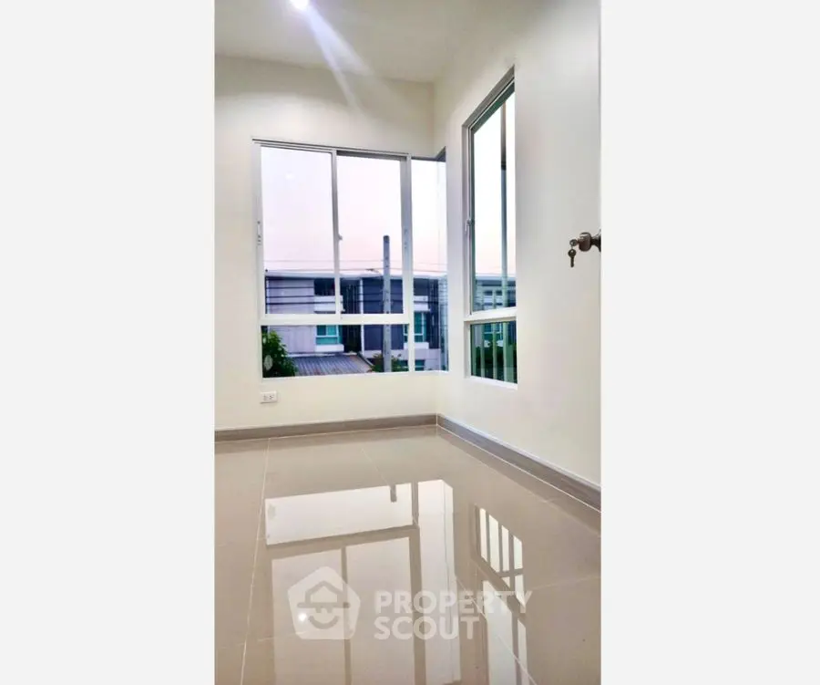 Bright empty room with glossy tiled floor and large windows offering a serene view.
