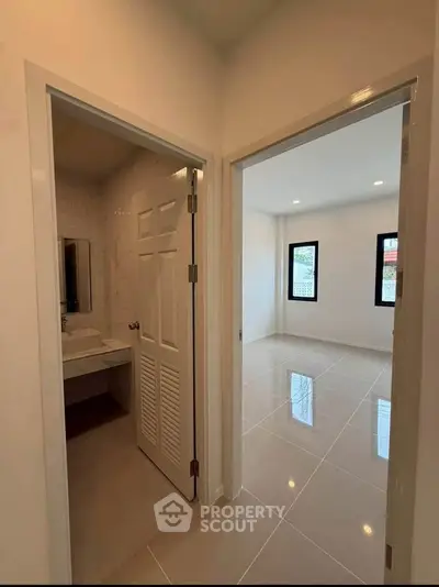 Modern apartment interior with bathroom and bright room, featuring sleek tile flooring and minimalist design.