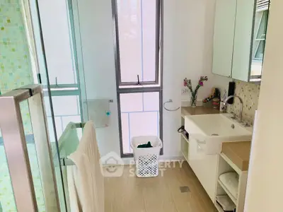 Modern bathroom with glass shower, large mirror, and stylish vanity in a bright apartment.
