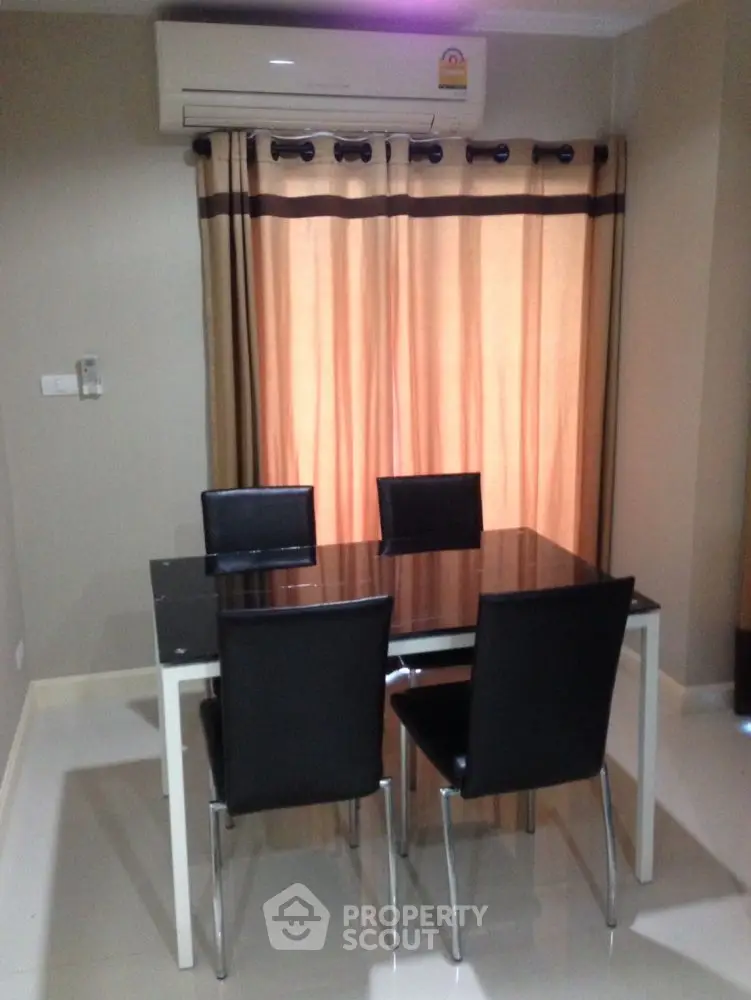 Modern dining area with sleek table and chairs under air conditioning unit.