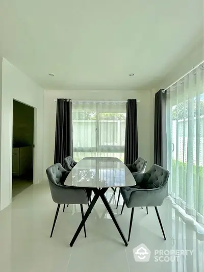 Elegant dining area with modern table and chairs, surrounded by large windows and natural light.