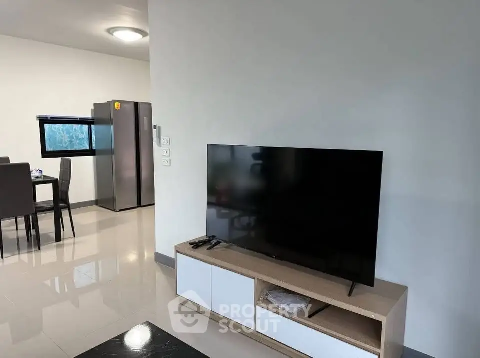 Modern living room with sleek TV and dining area, featuring contemporary furniture and bright lighting.