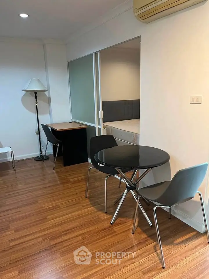 Modern apartment interior with wooden flooring, round dining table, and study area.