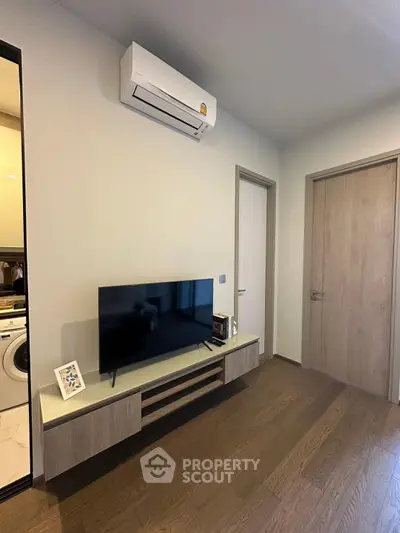Modern living room with sleek TV stand and air conditioning unit, featuring elegant wooden flooring.