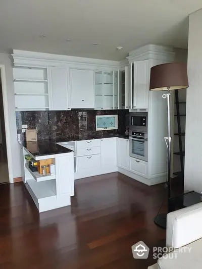 Modern kitchen with white cabinetry and dark marble backsplash in luxury apartment