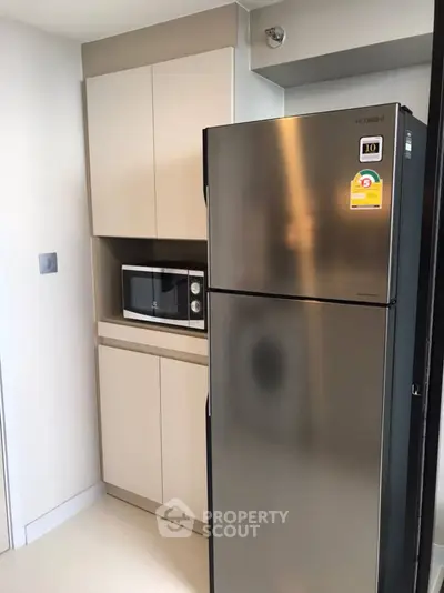 Modern kitchen with stainless steel fridge and built-in microwave in sleek cabinetry.