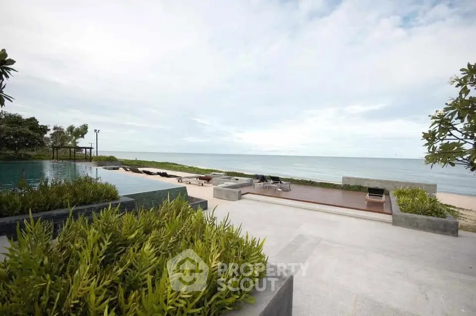Stunning beachfront pool area with ocean view and lush greenery.