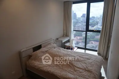 Cozy bedroom with city view, featuring a comfortable bed and modern furnishings.