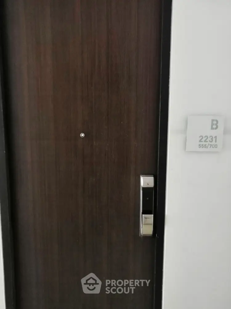 Modern apartment entrance with sleek wooden door and digital lock system.