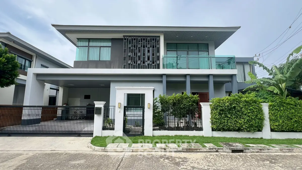 Modern two-story house with sleek design and lush greenery in a serene neighborhood.