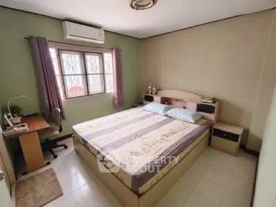 Cozy bedroom with large bed, desk, and air conditioning in a well-lit space.