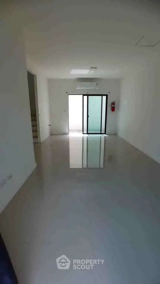 Spacious empty room with glossy floor and sliding glass door