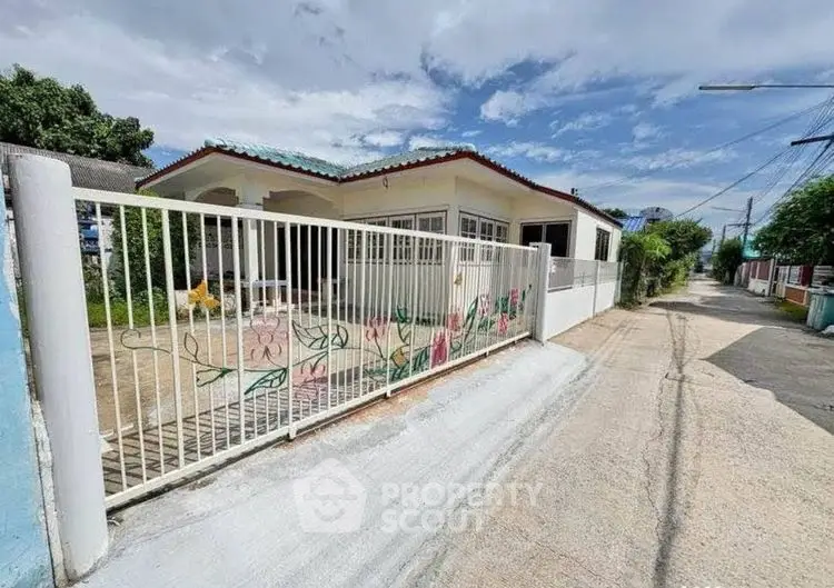 Charming single-story house with gated entrance and colorful fence art in a quiet neighborhood.