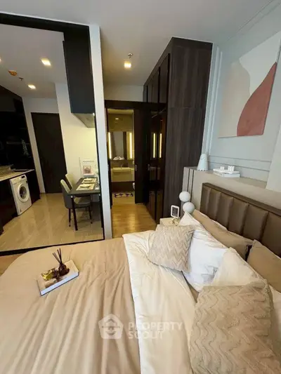 Modern bedroom with stylish decor and open view to kitchen and dining area, featuring elegant furnishings.