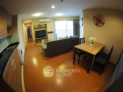 Modern open-plan living room with kitchen and dining area, featuring sleek wooden flooring and stylish decor.