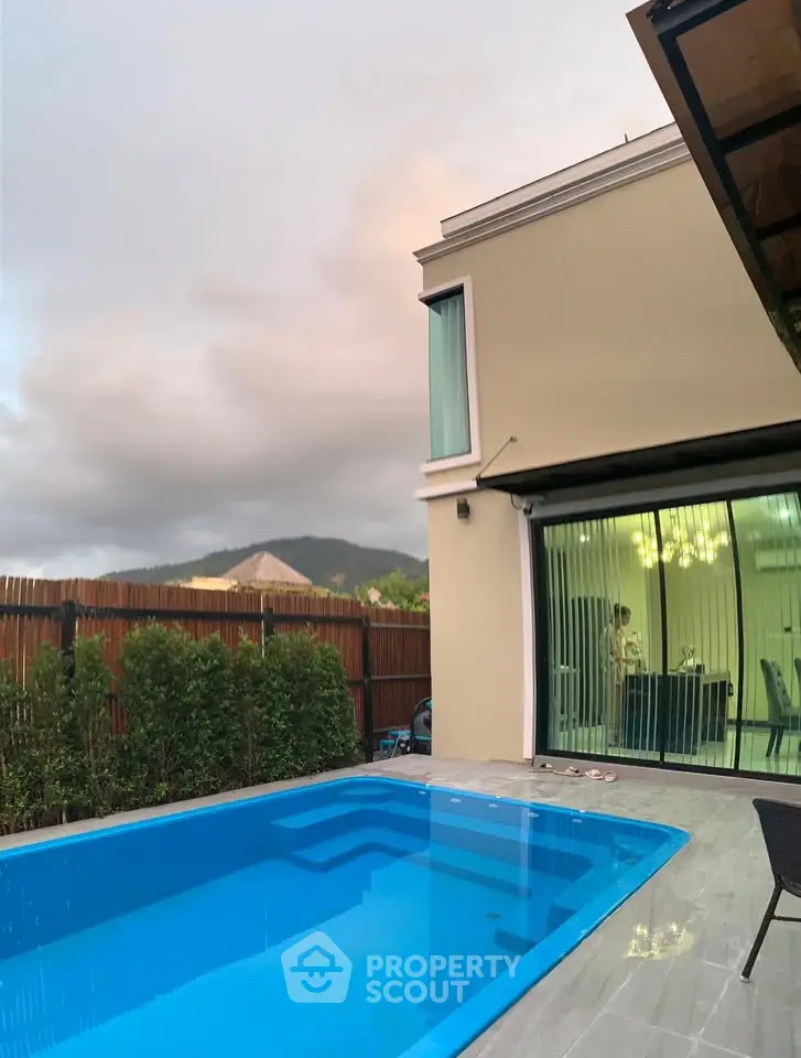 Modern villa with private pool and mountain view, featuring elegant glass doors and lush greenery.
